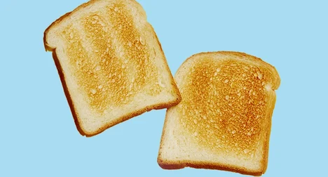 two slices of white golden toast in mid air on a blue background